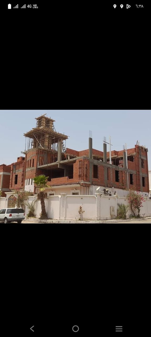 فيلا قيد الإنشاء بطوب أحمر وسقالات معدنية مع سور خارجي أبيض مكتمل