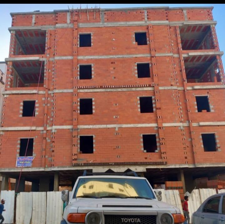 واجهة مبنى سكني من الطوب الأحمر بعدة طوابق وفتحات نوافذ قبل التركيب