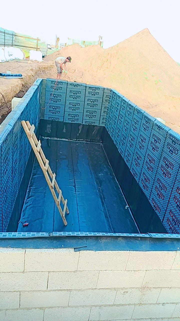 حفرة مسبح تحت الإنشاء مغطاة بألواح عزل زرقاء على الجدران والأرضية